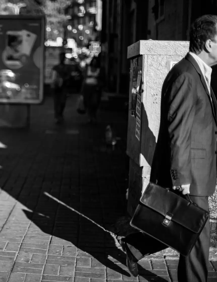 Business man walks past person laying in street